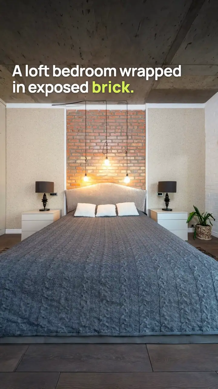 Vertical 9:16 cut of the city loft listing video: a loft bedroom with an exposed brick wall and pendant lights with the line "A loft bedroom wrapped in exposed brick."